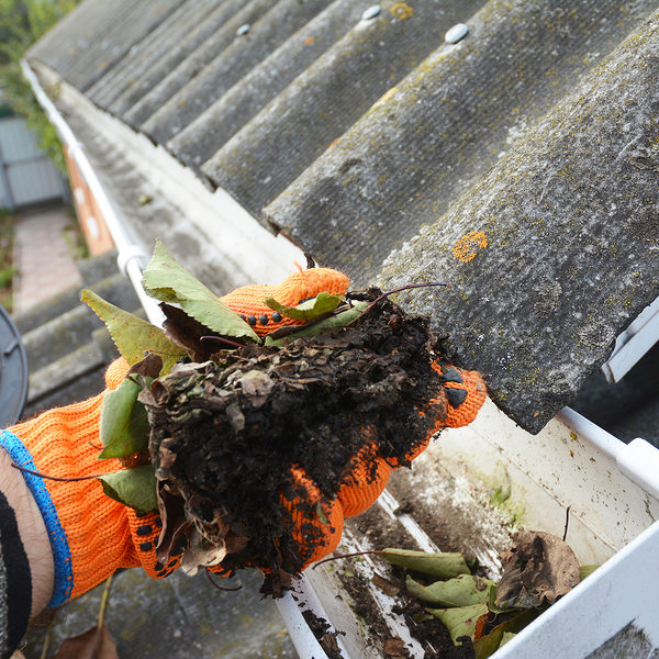 Rain Gutter Cleaning. Scooping leaves from gutter. Clean and Repair Rain Gutters and Downspout with roofer hands. Step by Step.